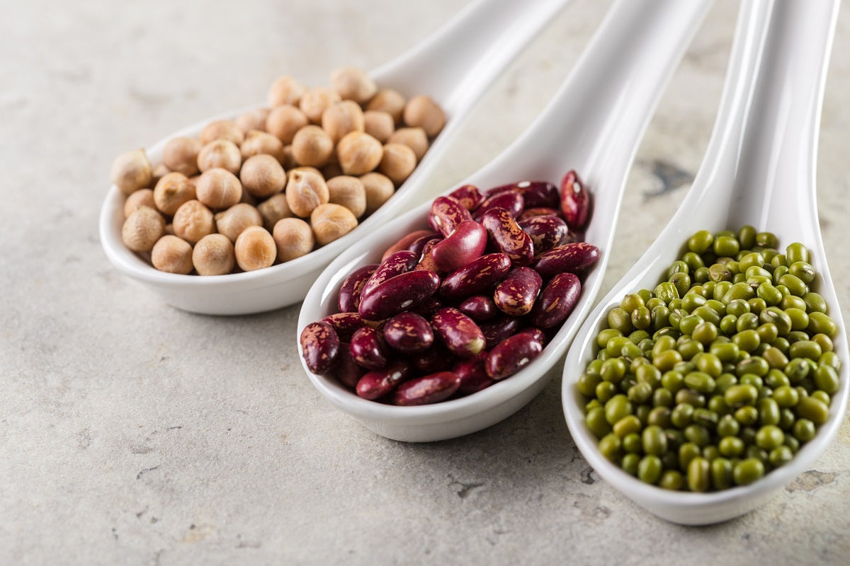 Erbsen, Bohnen und Kichererbsen auf Keramiklöffeln