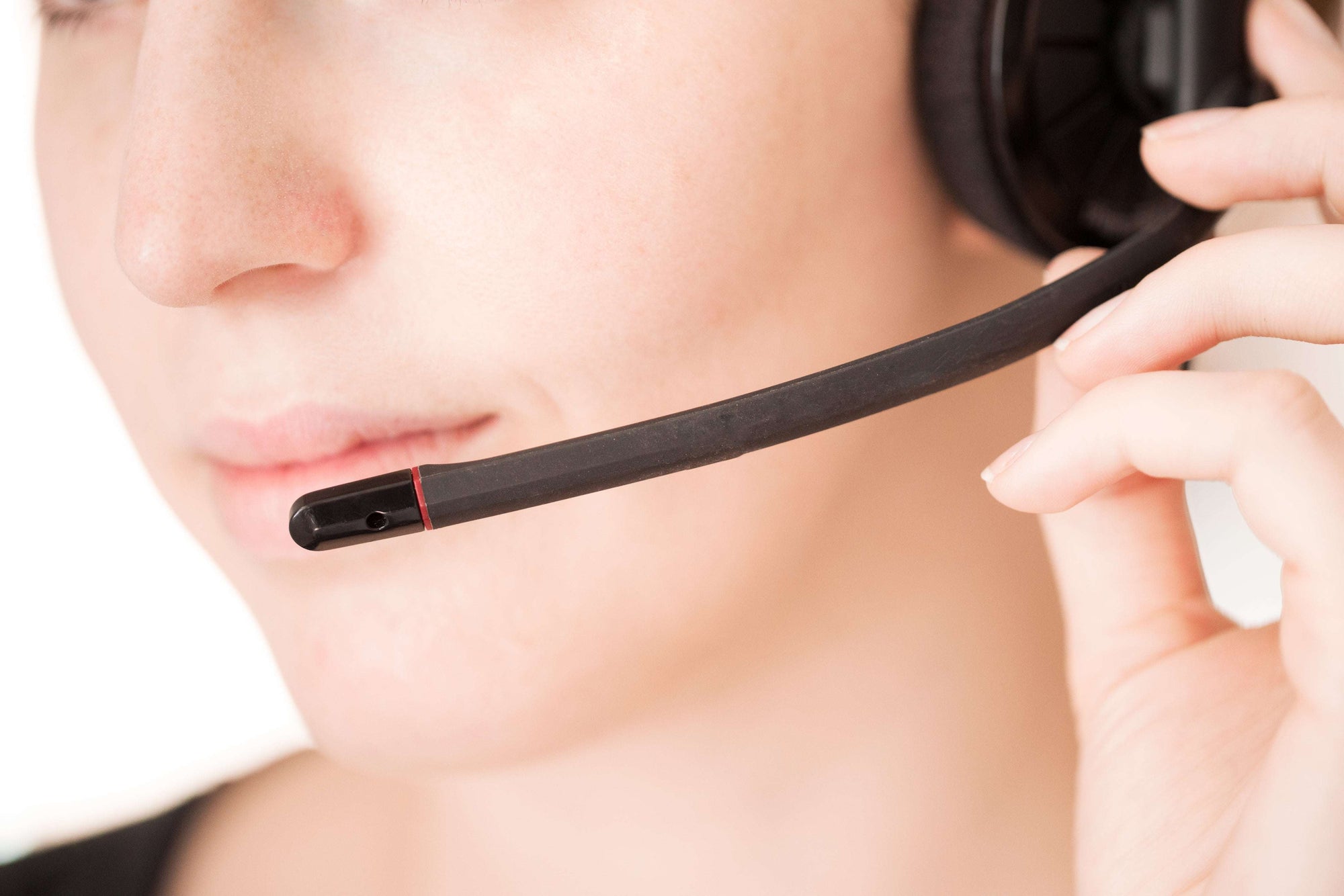 Nahaufnahme einer Frau mit einem Headset, das sie mit einer Hand locker am Ohr festhält