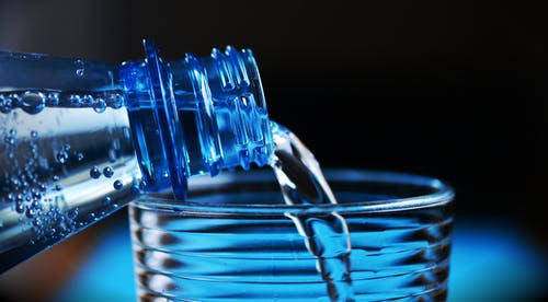 Mineralwasser wird aus Flasche in Glas gegossen