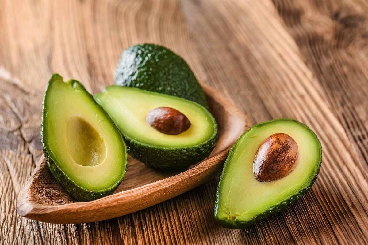 Avocados in einer Holzschale auf einem Holztisch