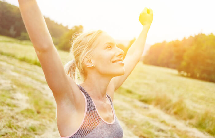 Gesunde Ernährung ab 40: Eine Frau beim Sport in der Natur freut sich, dass sie durch Bewegung und gesunder Ernährung mehr Lebensfreude besitzt.
