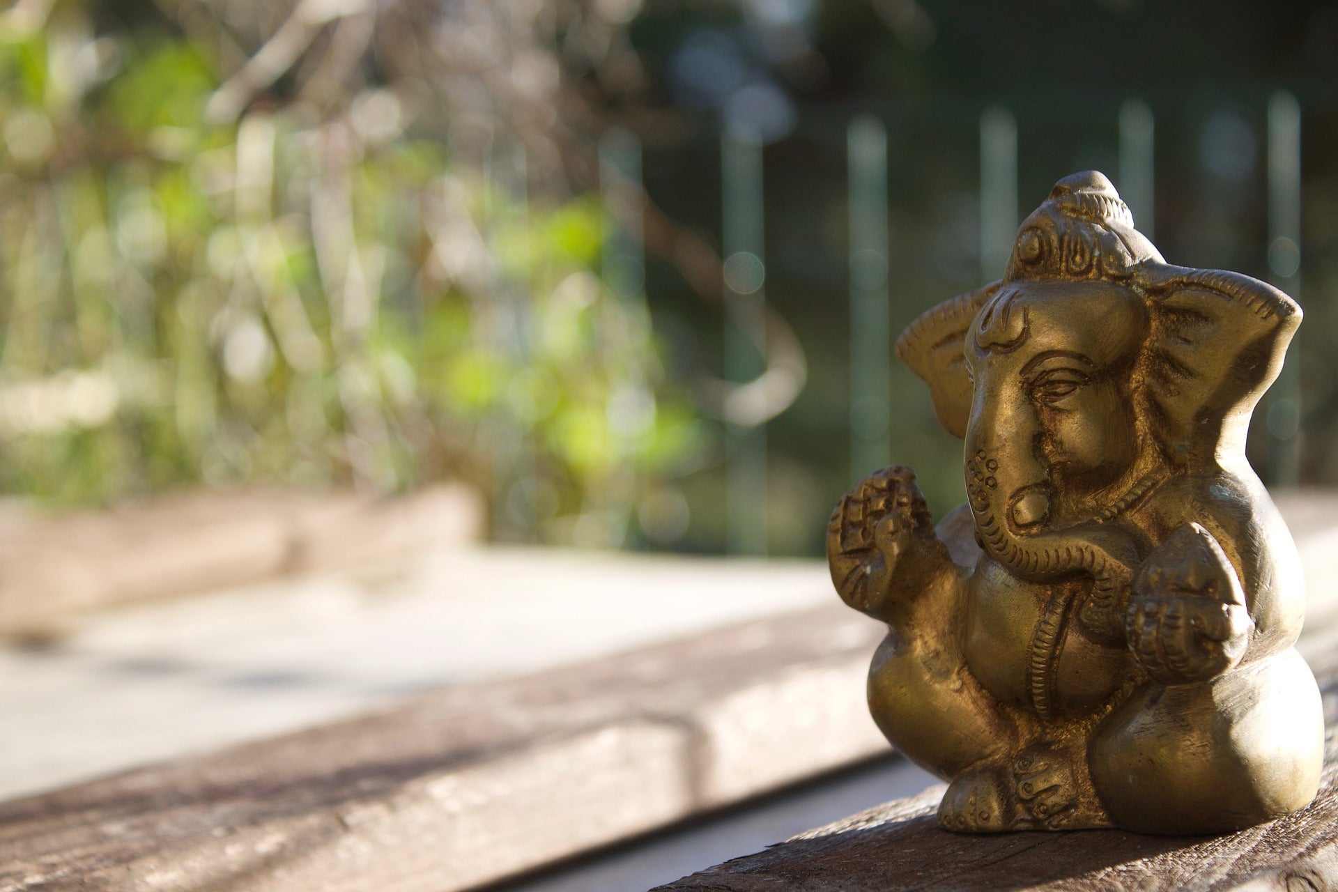 Goldfarbene Elefantenskulptur auf einer Holzunterlage vor einem natürlichen Hintergrund - ein Symbol für Yoga