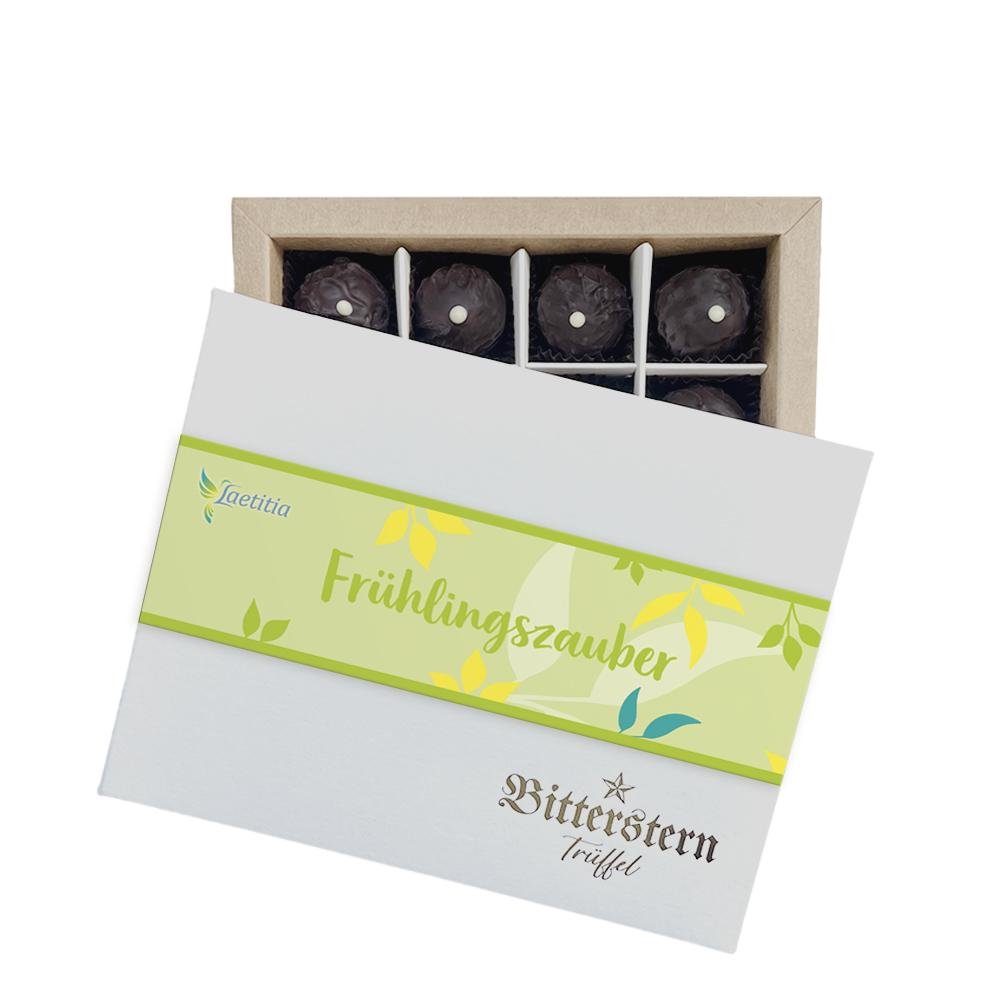 Schachtel mit 12 Original Bitterstern-Trüffeln, Frühlingsedition, verziert mit grüner Verpackung und gelben Blattmotiven.