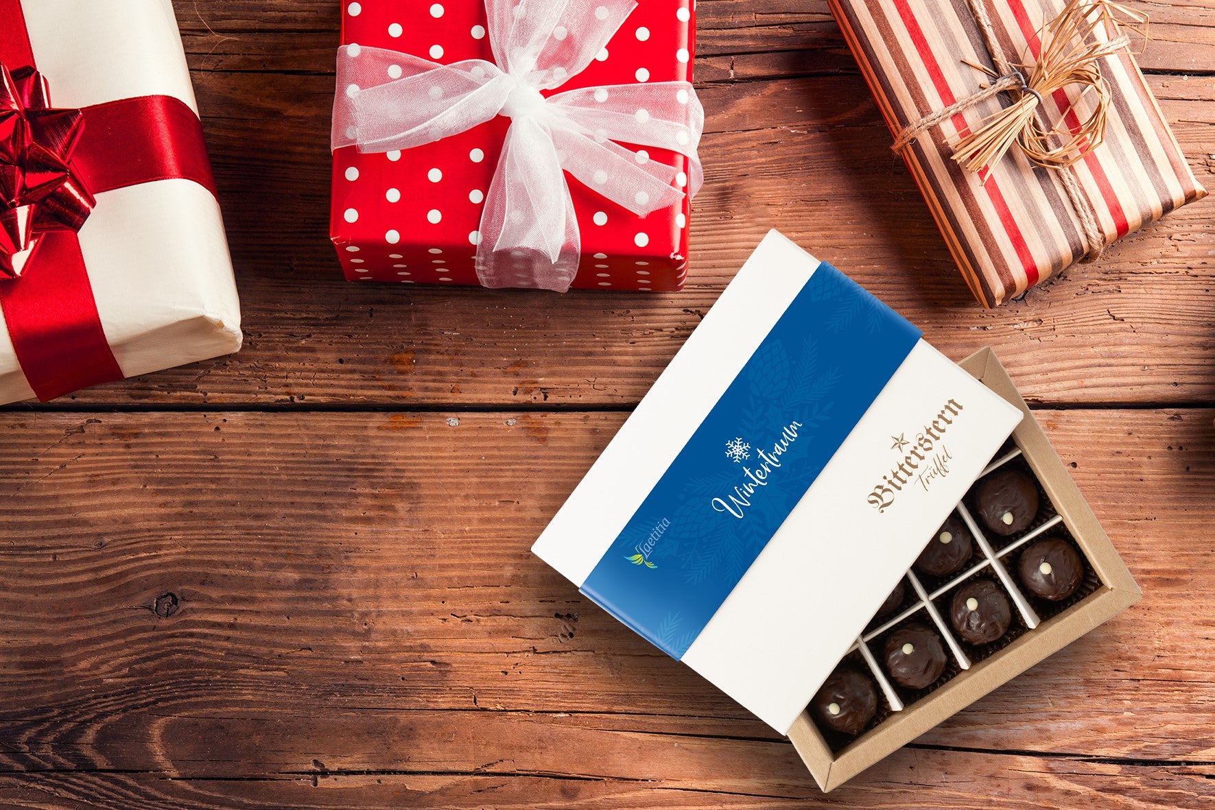 eingepackte Geschenke und Laetitia Bitterstern Trüffel Geschenkverpackung liegen auf Holzuntergrund