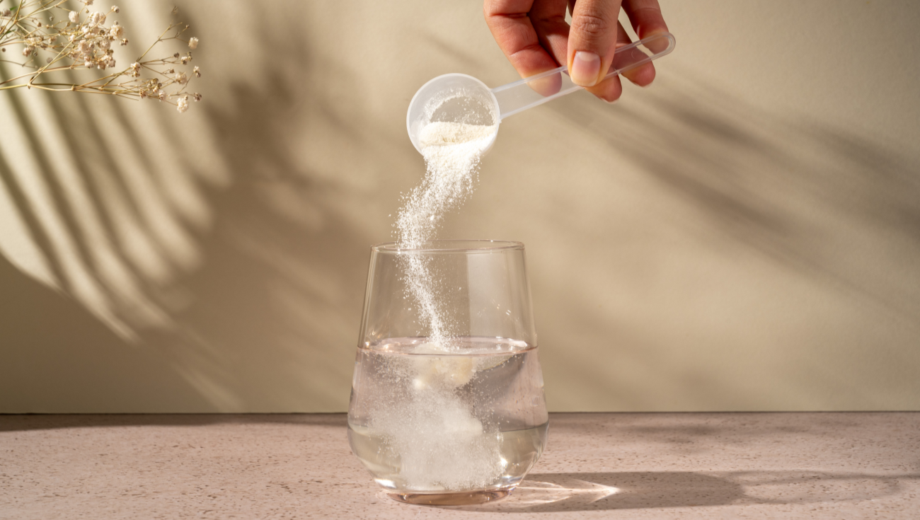 Basenpulver wird mit Dosierlöffel in ein Glas gekippt