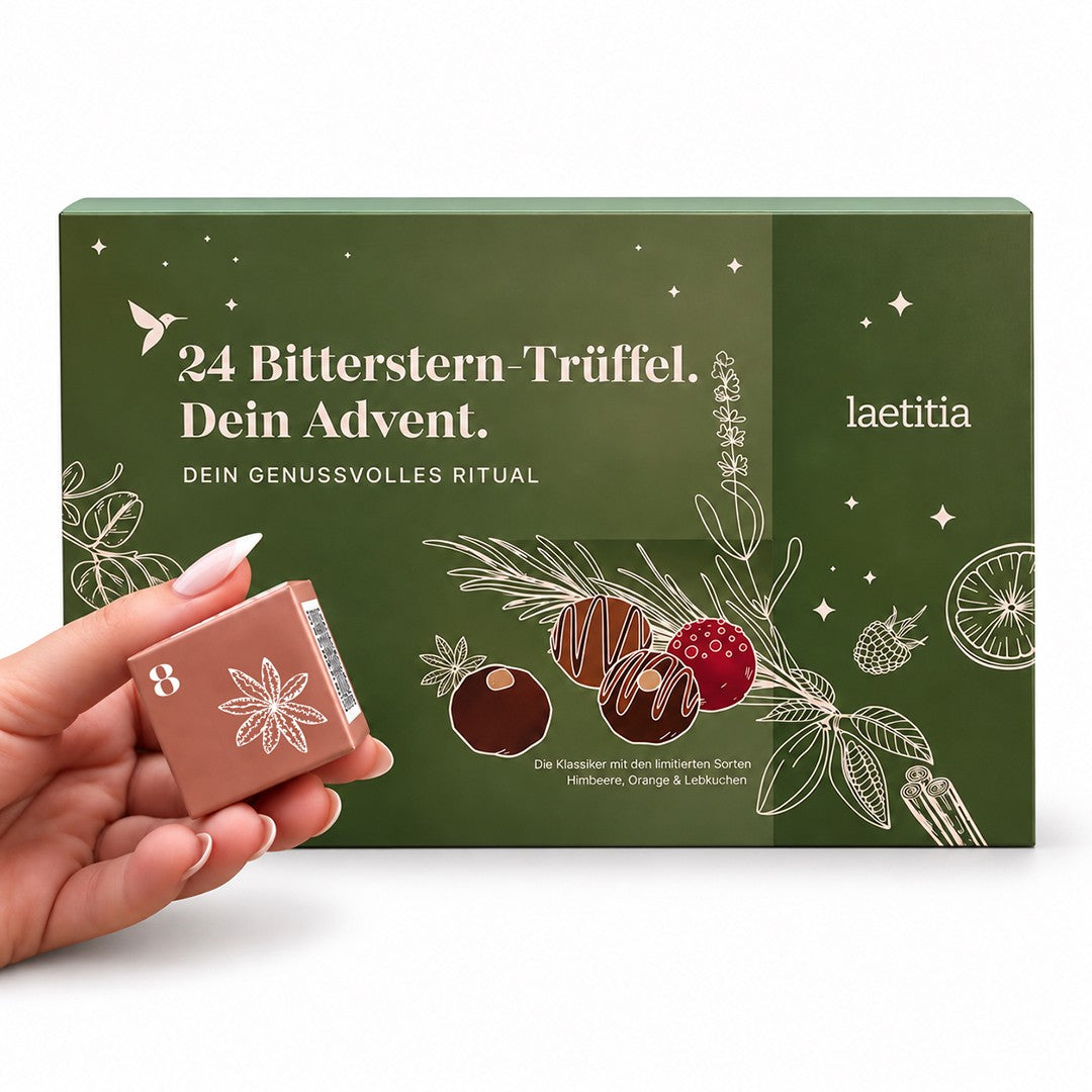 Bitterstern Trüffel Adventskalender mit 24 Schokoladentrüffeln und drei neuen Sorten Himbeere, Orange und Lebkuchen, davor eine Hand mit einem nummerierten Adventskalender-Türchen.