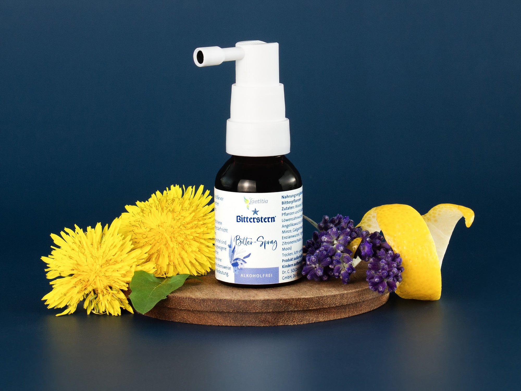 Bitterstern Bitter-Spray von Laetitia auf einem Holztablett, hergerichtet mit Blüten und einer Zitronenschale vor blauem Hintergrund. 