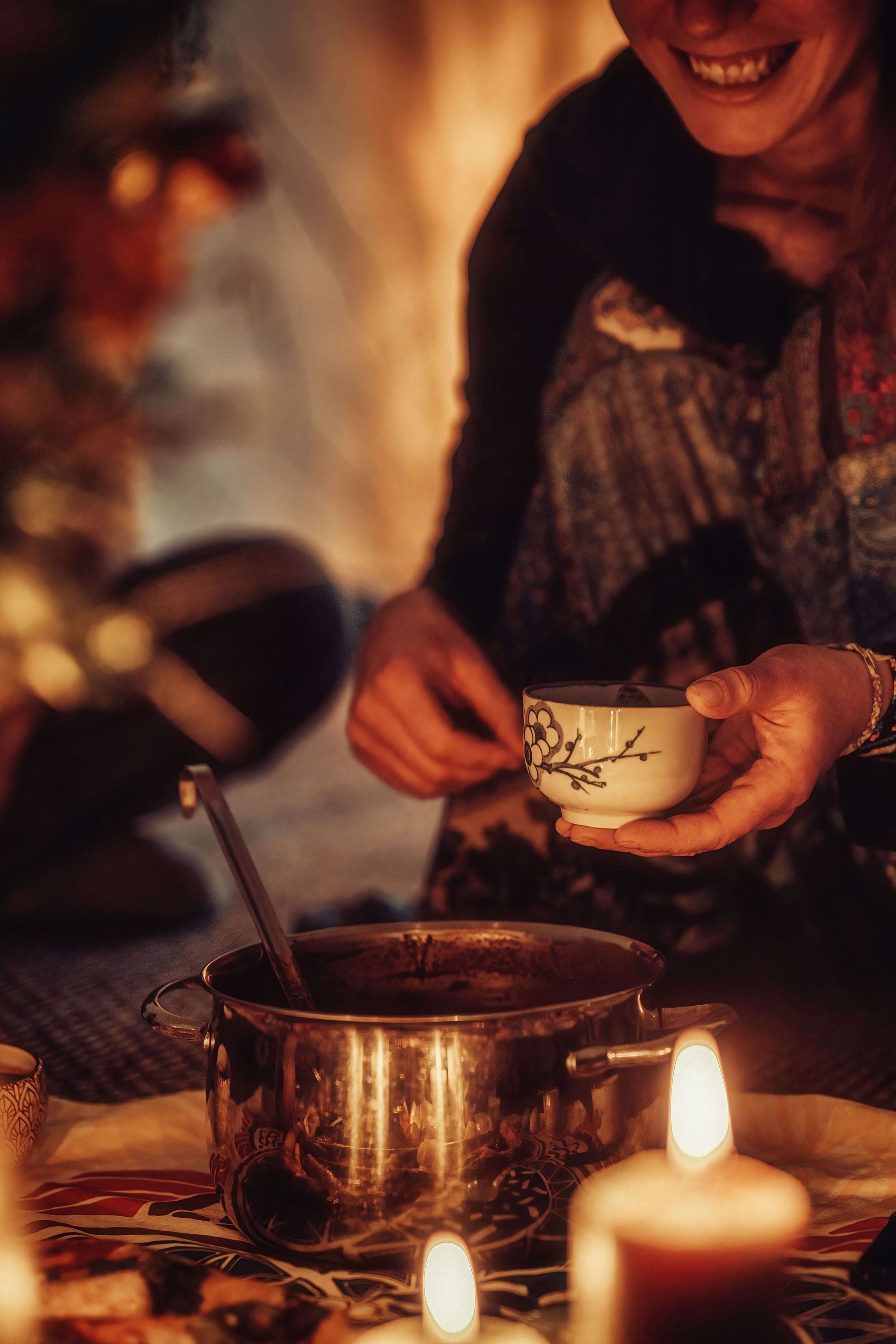 Bei einer Kakaozeremonie wird Kakao ausgeschenkt, aus einem Topf, außen herum Kerzen für eine spirituelle Stimmung