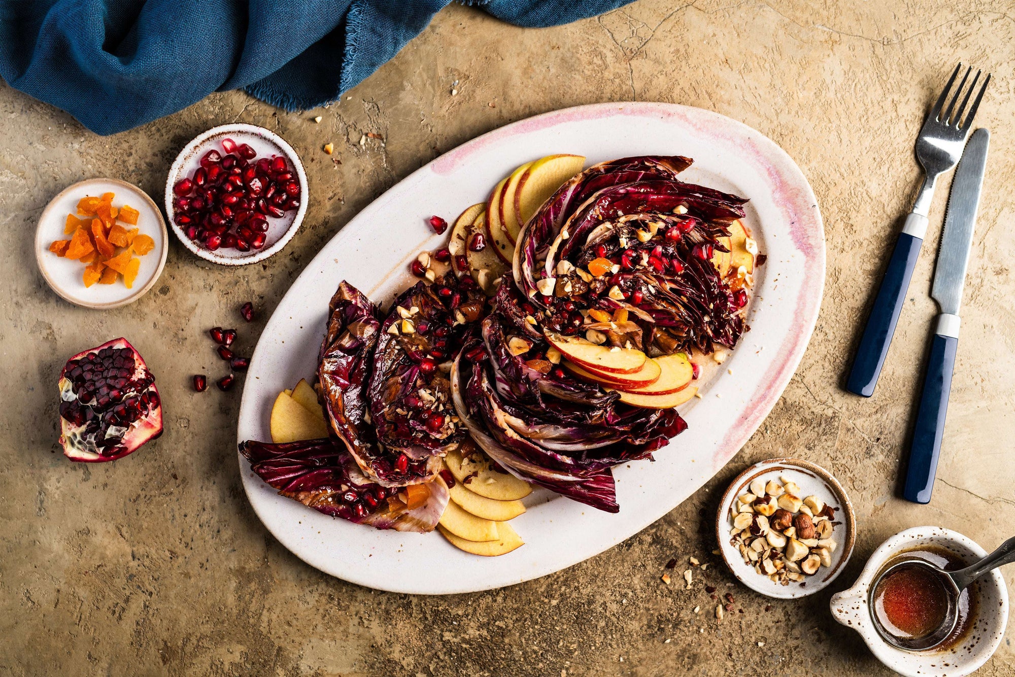 Gegrillter Radicchio auf einem weißen Teller mit Apfelscheiben und Granatapfelkernen, garniert mit Nüssen — ein farbenfrohes, basisches Rezept für eine basische Ernährung.