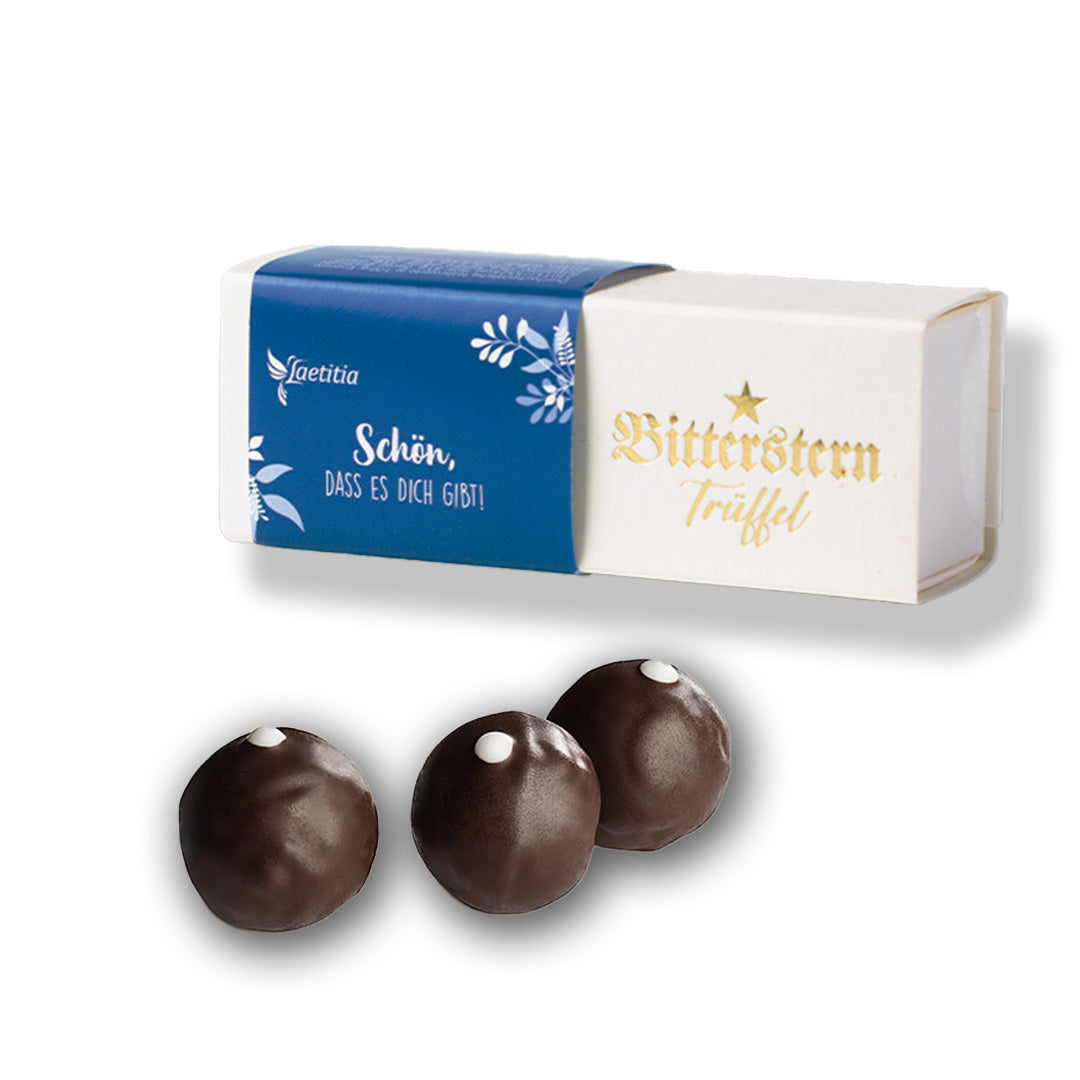 Drei Schokoladentrüffel und deren Verpackung im Hintergrund