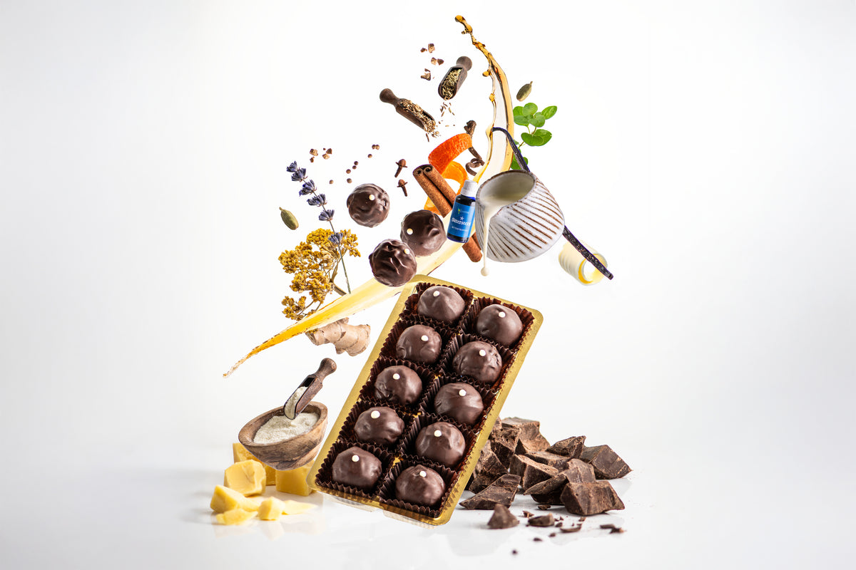 Bittertstern Schokoladentrüffel mit all seinen Zutaten, von Lavendel, Zimt, Ingwer bis Kakao - schwebend dargestellt, sowie 3 fliegenden Pralinen über dem Produkt
