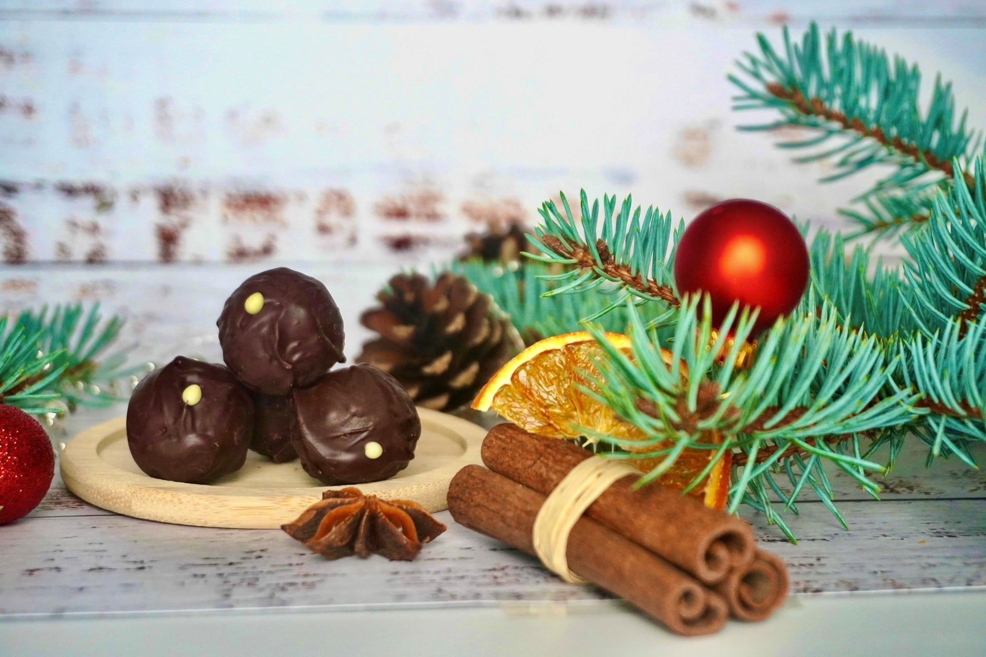 Bitterstern Schokoladentrüffel von Laetitia mit weihnachtlicher Dekoration, Zimtstangen, Weihnachtskugeln und Tannenzweigen.