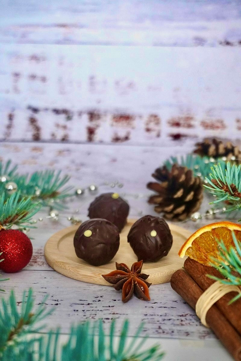 Bitterstern Schokoladentrüffel von Laetitia mit weihnachtlicher Dekoration, Zimtstangen, Weihnachtskugeln und Tannenzweigen.
