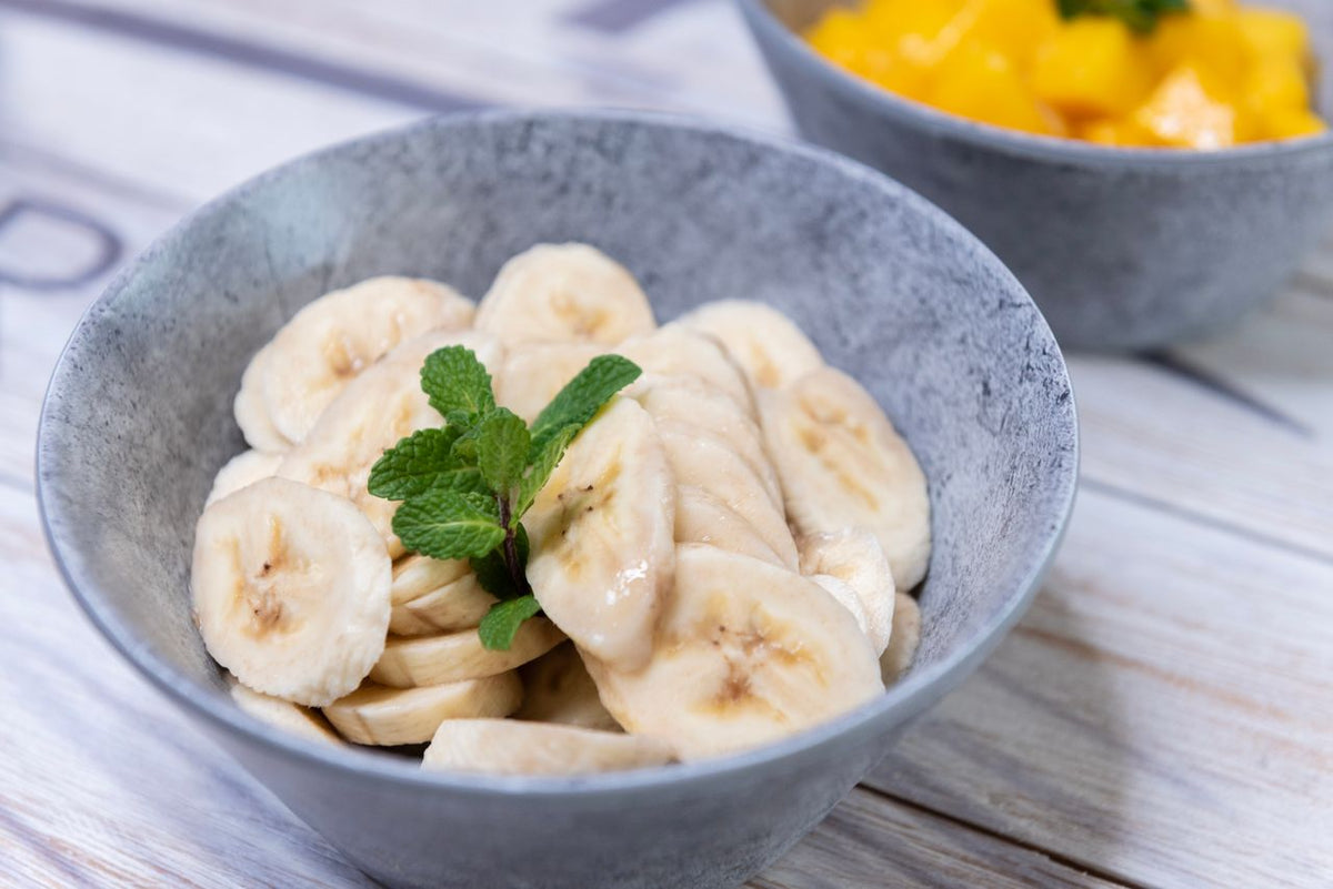 Geschnittene Bananen mit Minze in einer Schale – Bananen zählen zu den basischen Lebensmitteln und passen zu einer basenreichen Ernährung.