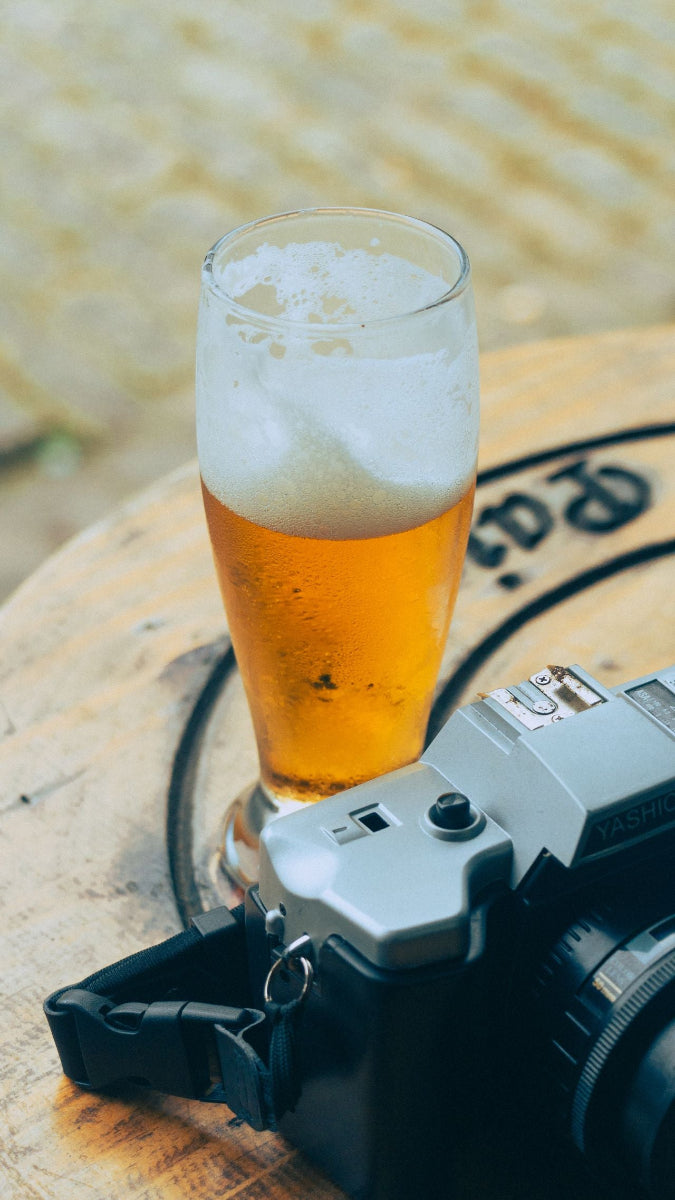 Glas mit Bier neben einer Kamera – Bier zählt zu den basisch verstoffwechselten Getränken