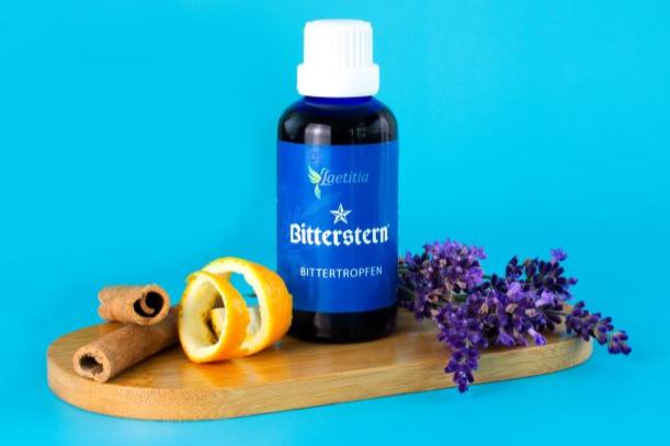 Bitterstern Bittertropfen dekoriert mit Zimt, Pomeranzenschale und lila Blüten