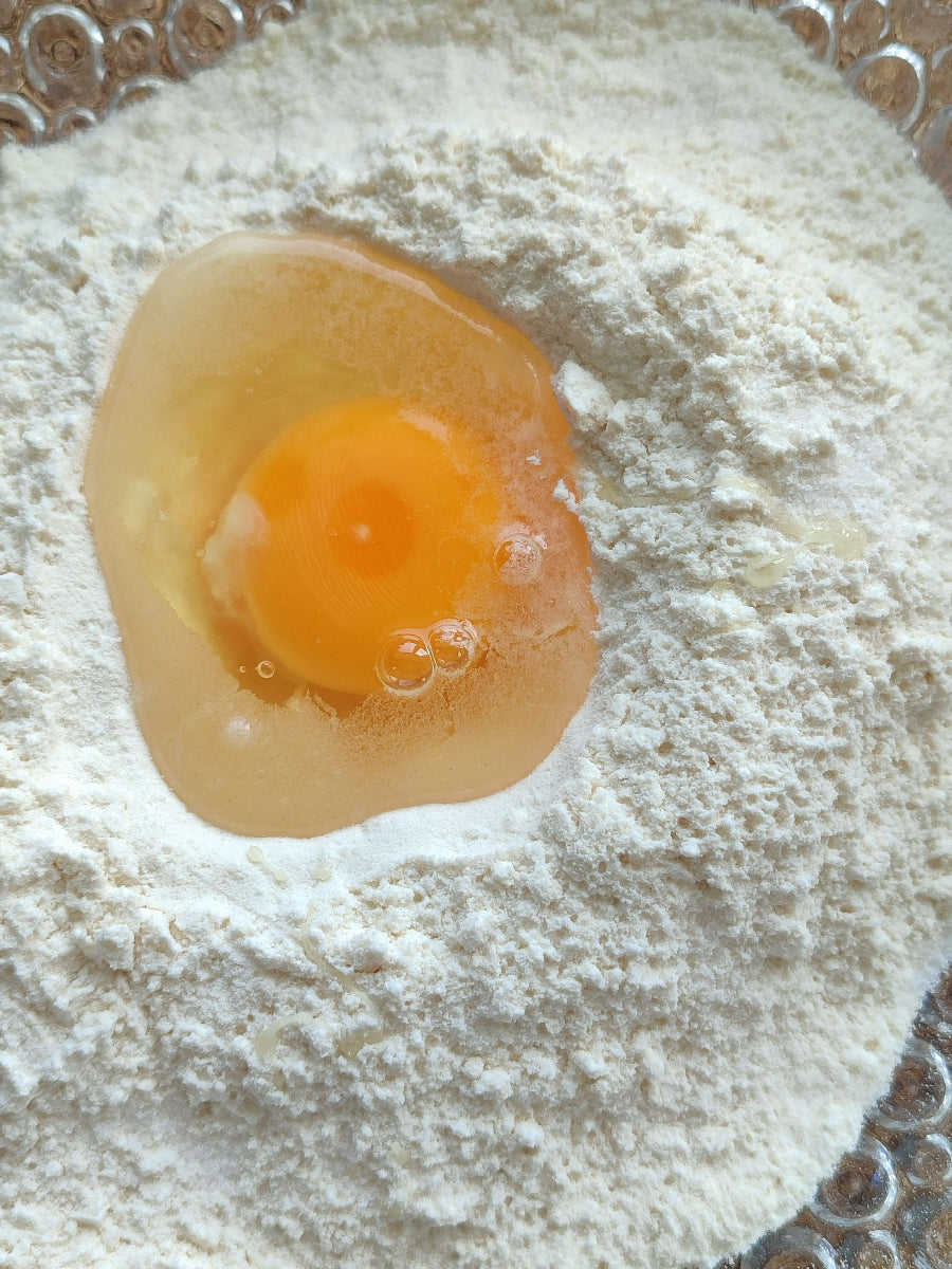 Rohes Ei in einer Schüssel mit Mehl als Zutat zum Backen oder Kochen. Das Bild veranschaulicht das Thema „Sind Eier basisch oder säurebildend?“ im Rahmen einer basischen Ernährung.