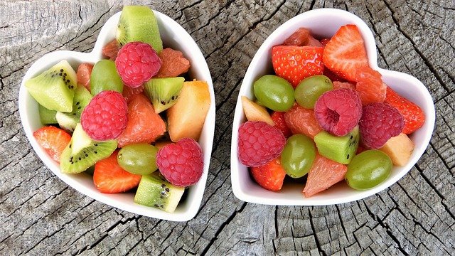 frisches Obst (Kiwi, Himbeere, Erdbeere, Weintraube) in zwei weißen Keramikschüsseln