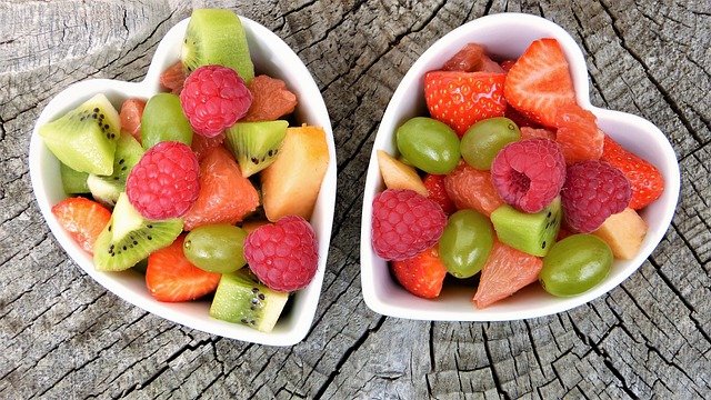 frisches Obst (Kiwi, Himbeere, Erdbeere, Weintraube) in zwei weißen Keramikschüsseln ist gut zur Entsäuerung