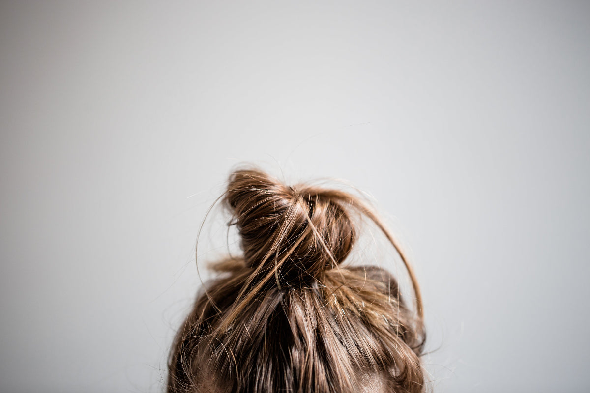 Haare einer Frau zu einem Dutt gebunden