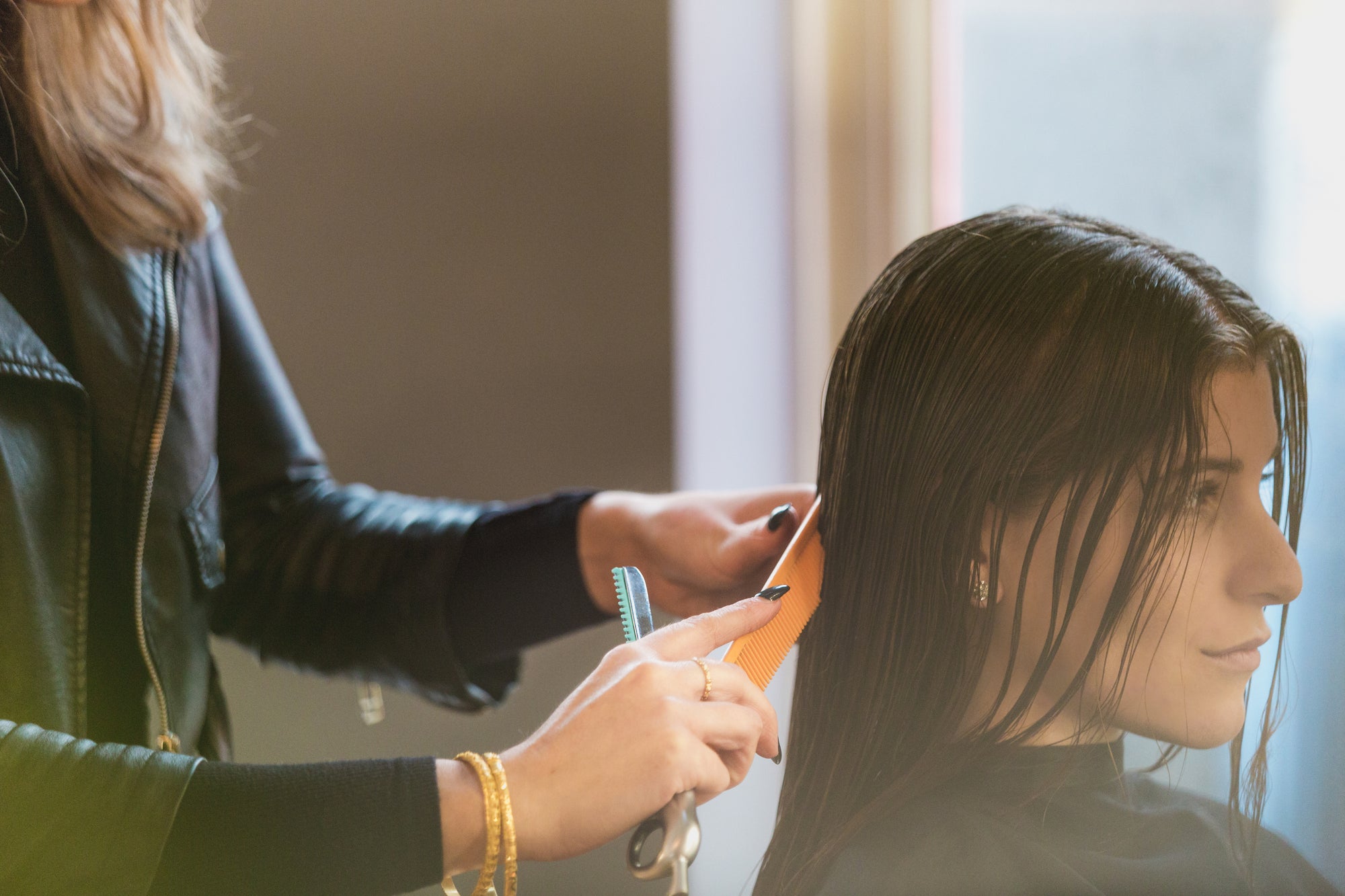 Friseurin trägt eine pflegende Haarmaske auf langes dunkles Haar auf – natürliche Haarkur für glänzende und gesunde Haare mit basischer Haarpflege.