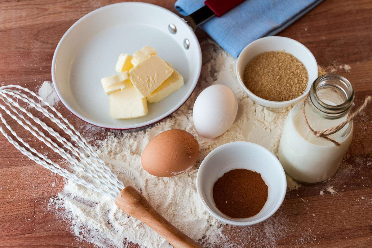 Butter mit Ei, Mehl, Milch und weiteren Backzutaten auf einer Arbeitsfläche. Das Bild begleitet die Frage „Ist Butter basisch oder säurebildend?“ im Zusammenhang mit der basischen Ernährung.
