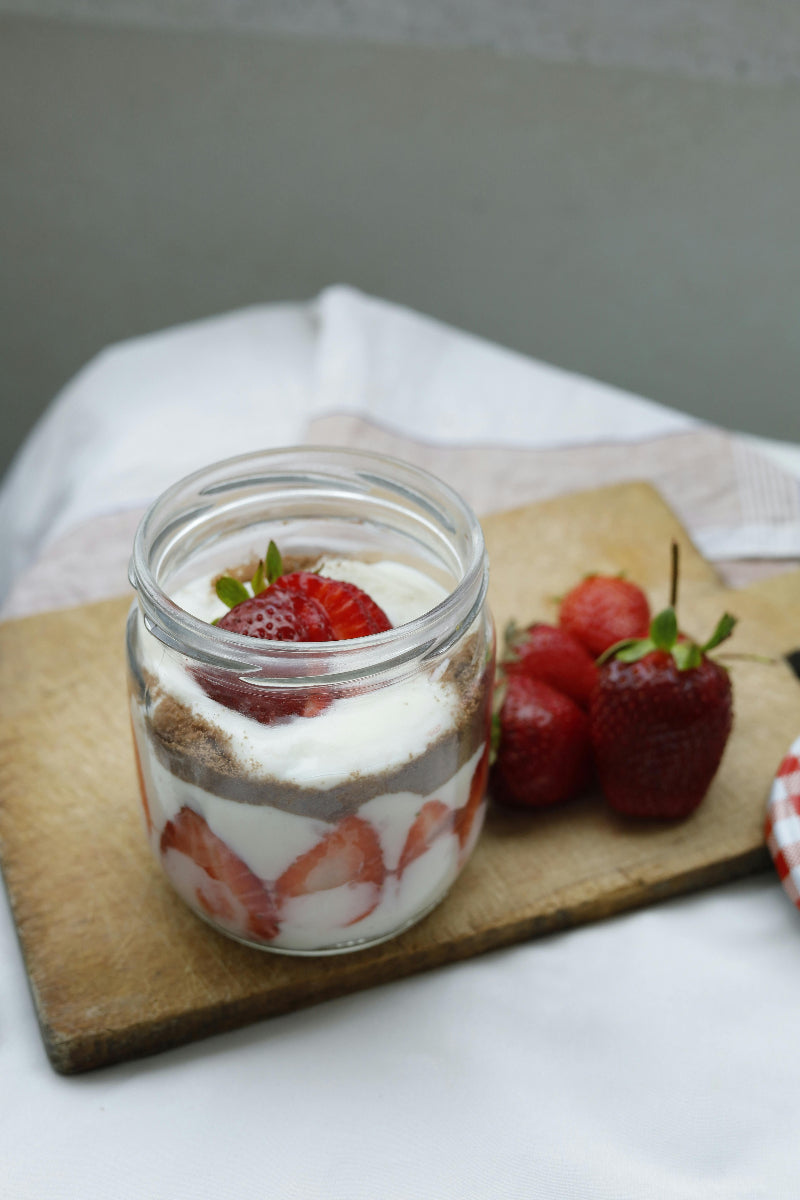 Schichtdessert aus Naturjoghurt und Erdbeeren im Glas. Der Artikel erklärt, ob Joghurt basisch ist und welche Rolle das Milchprodukt in einer basenüberschüssigen Ernährung spielt.