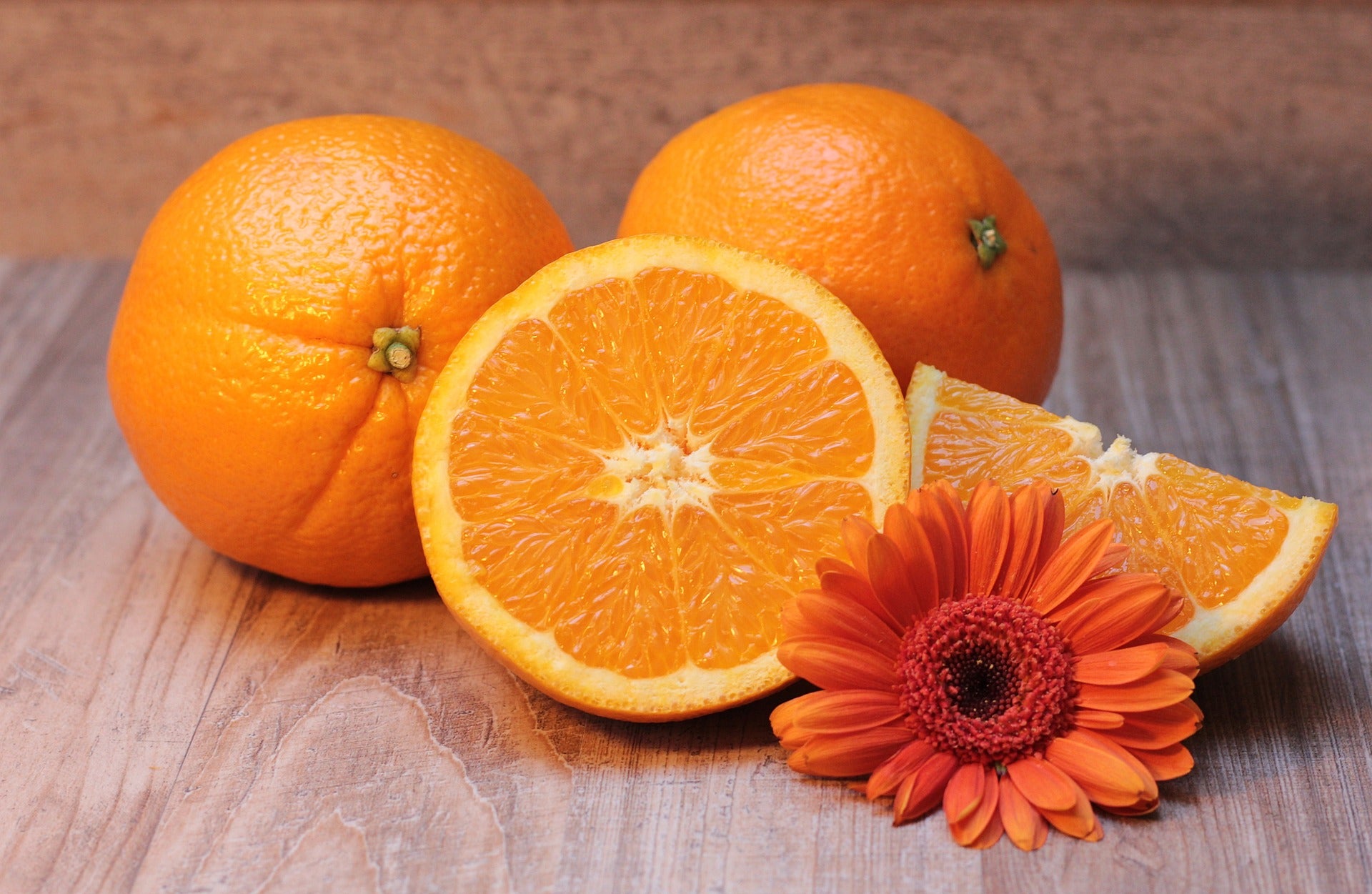 Orangen - ganz und aufgeschnitten mit einer orangenen Blüte