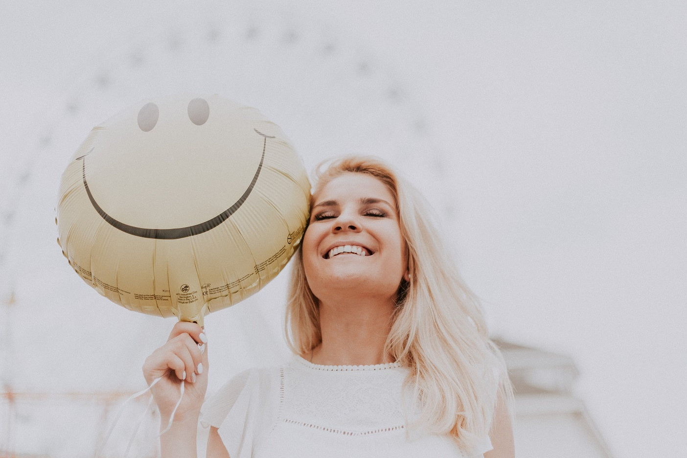 Frau mit einem Smiley-Luftballon in der Hand