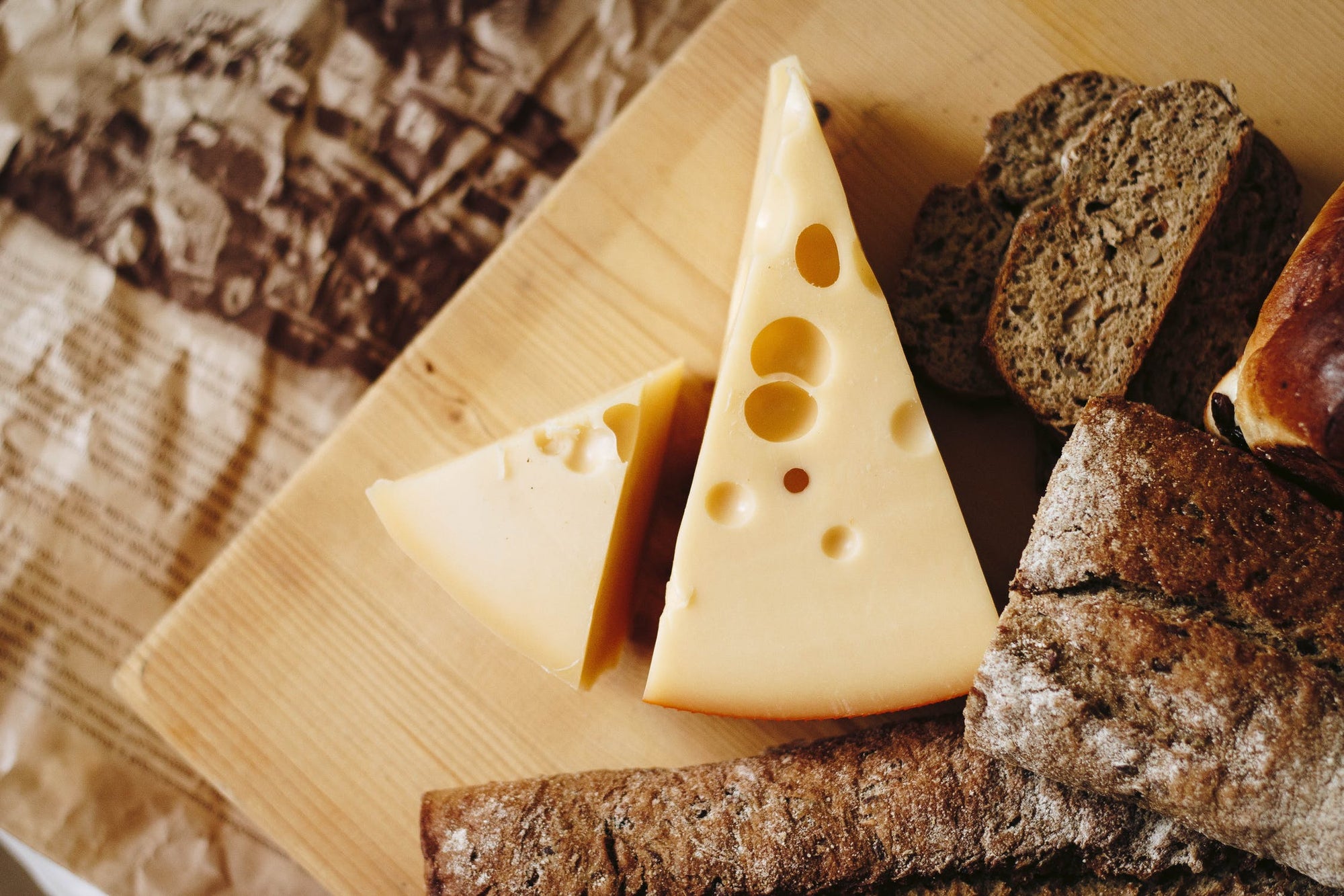 Emmentaler Köse liegt mit Brotstücken auf Holzbrett