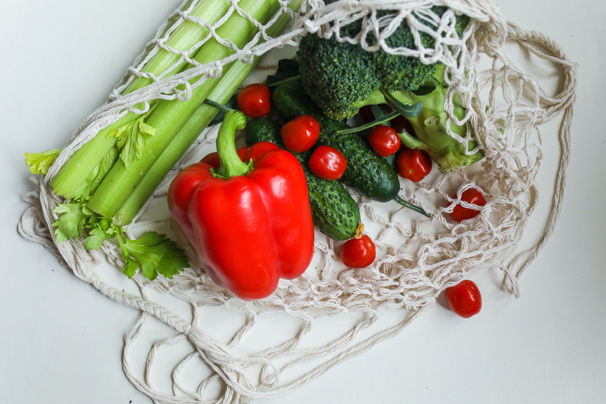 Gemüse (Sellerie, Paprika, Tomaten, Gurken, Brokkoli) in Einkaufsnetz