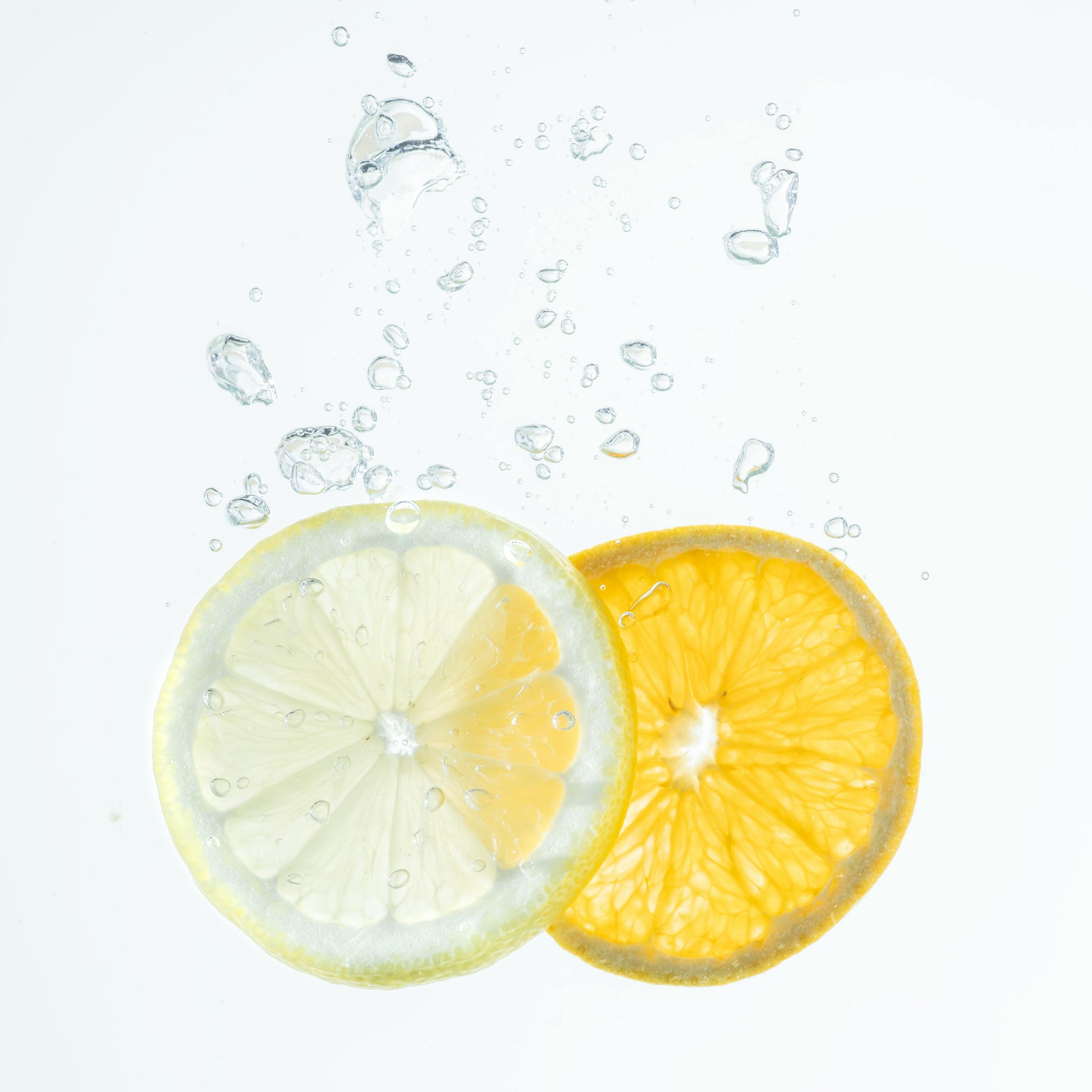 Zitronen- und Orangenscheibe gleiten ins Wasser