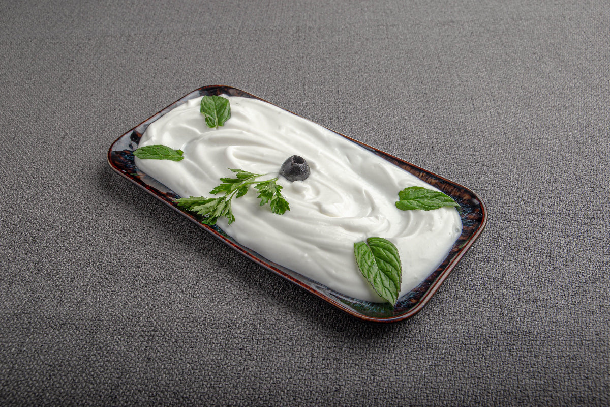 Schale mit cremigem Quark, garniert mit frischer Minze und Petersilie. Das Bild begleitet die Frage „Ist Quark basisch oder säurebildend?“ im Zusammenhang mit der basischen Ernährung.