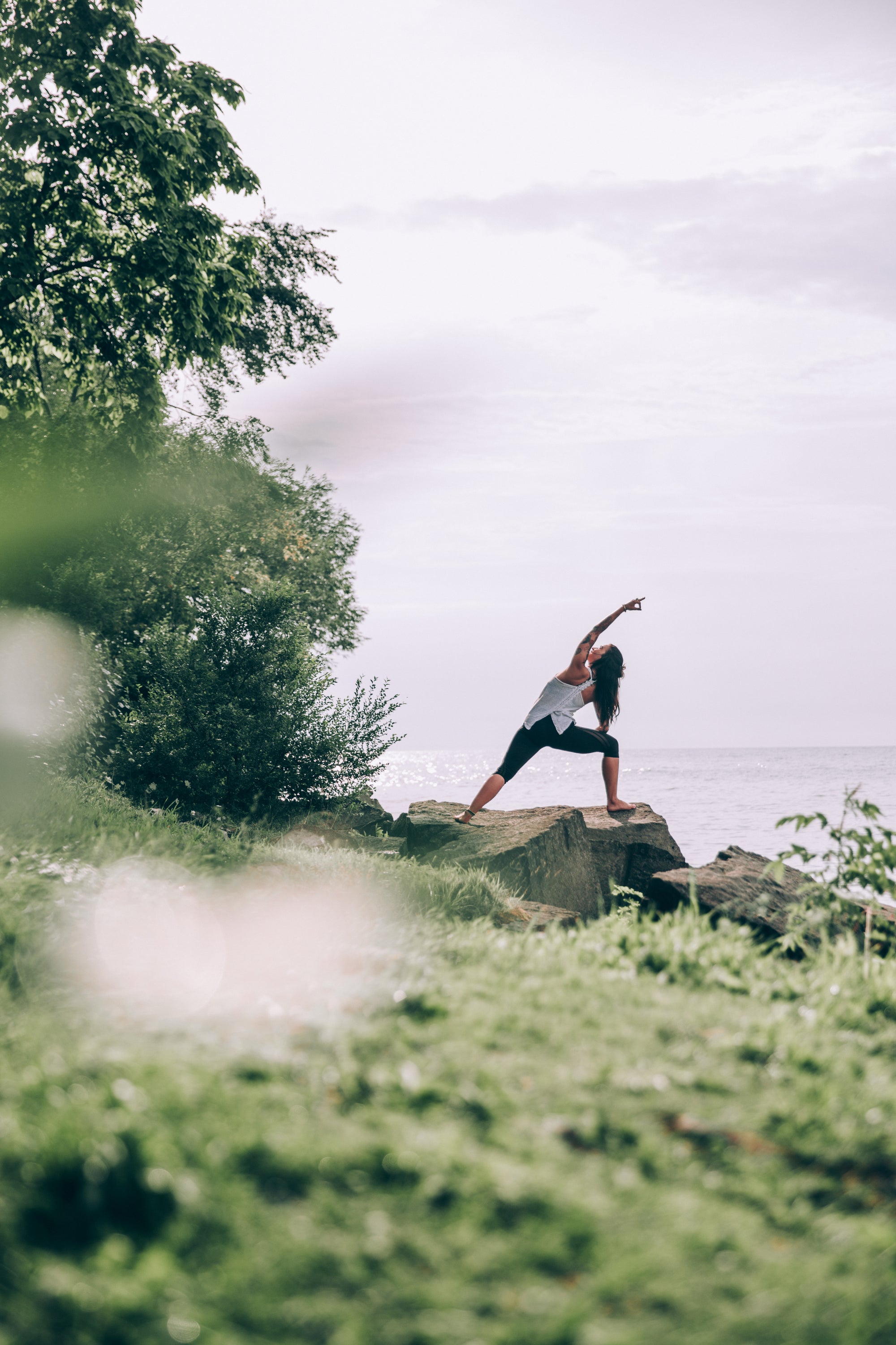 Frau stärkt Ihr Immunsystem mit Yoga auf einer Klippe am Meer.