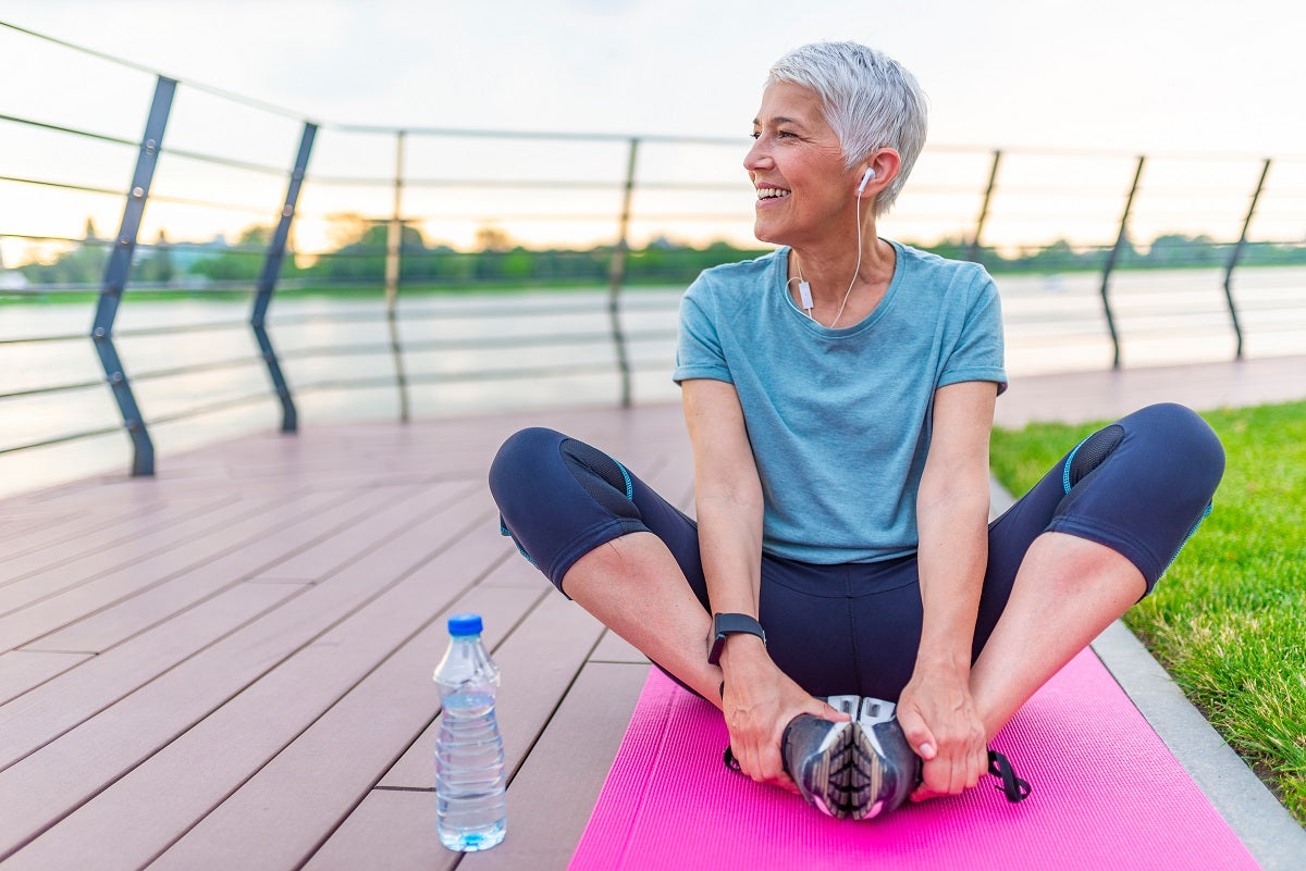 Frau mit grauen Haaren auf einer pinken Yogamatte