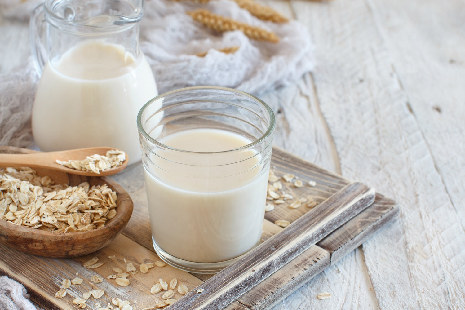 Hafermilch in einem Glas neben einem Löffel Haferflocken. Hafermilch ist nicht basisch