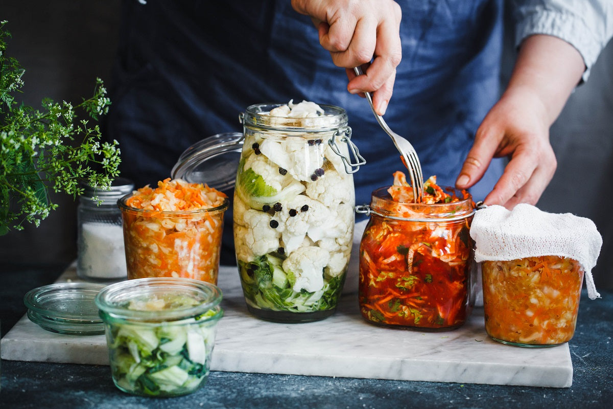 Fermentierte Lebensmittel in Gläsern - mit einer Gabel werden fermentierte Lebensmittel entnommen. 
