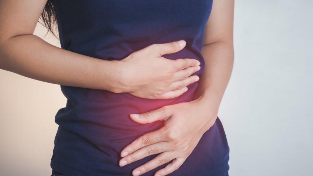 Frau hält sich den Bauch wegen Luft im Bauch und Blähungen
