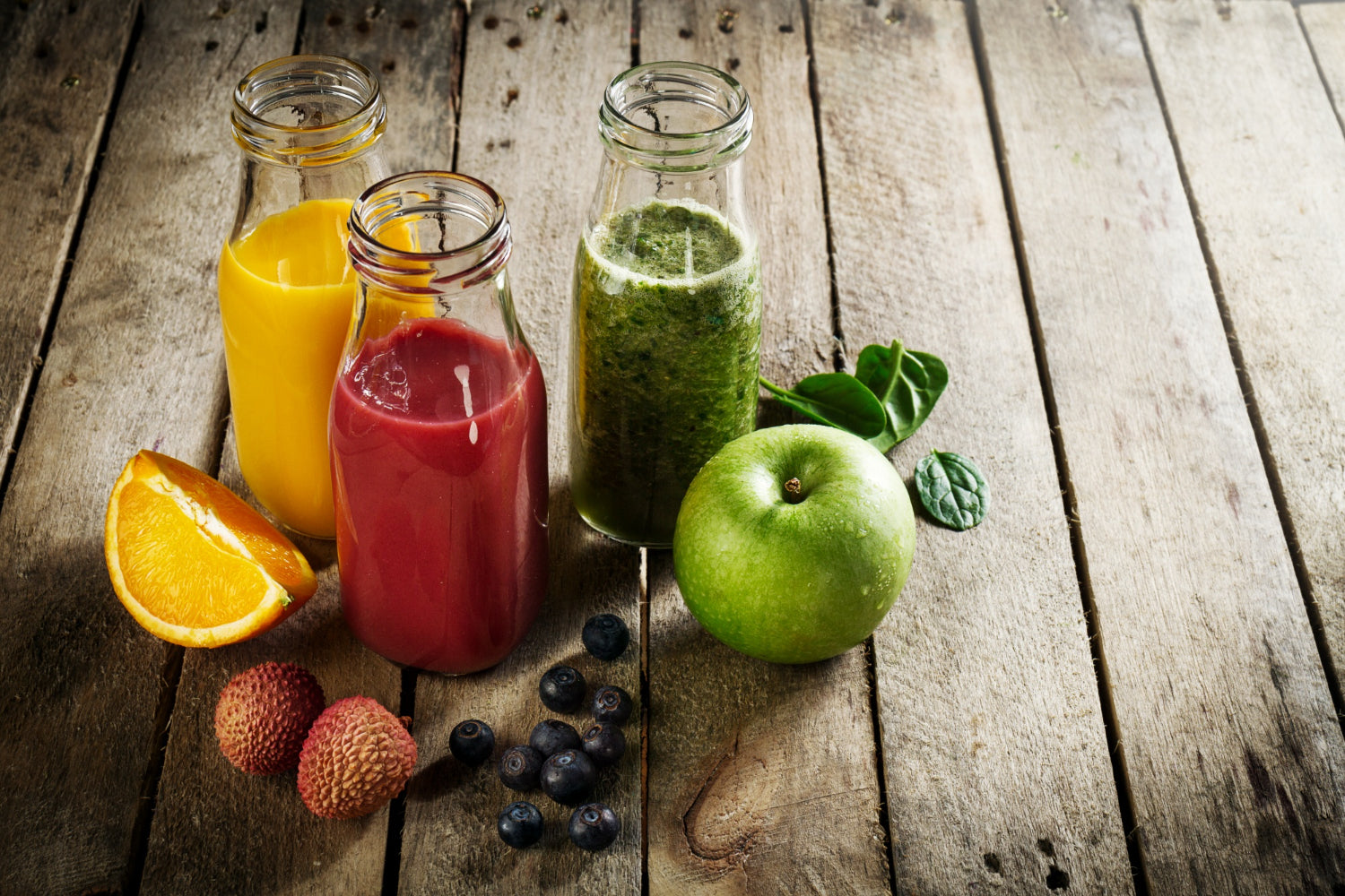 Eine Entschlackungskur mit Obst und Smoothies in Flaschen auf einer Holzunterlage