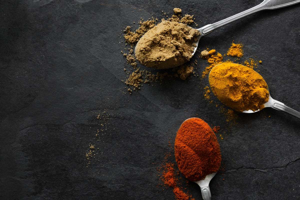 Gewürze auf Löffeln auf einer Schiefertafel