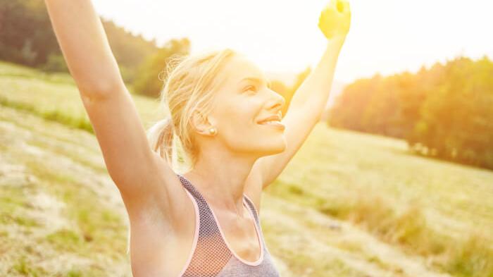 Gesunde Ernährung ab 40: Eine Frau beim Sport in der Natur freut sich, dass sie durch Bewegung und gesunder Ernährung mehr Lebensfreude besitzt.